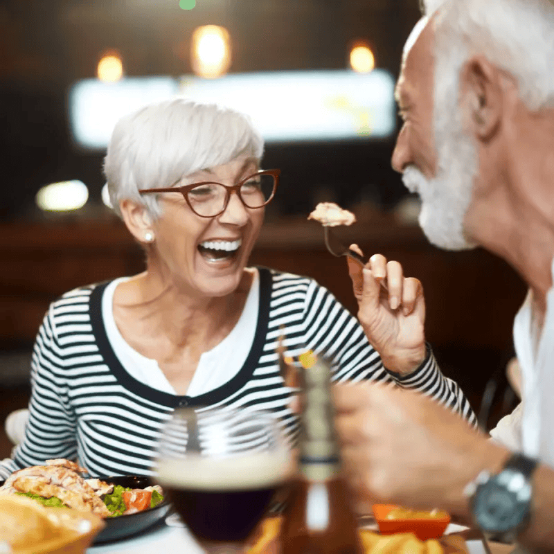 senior woman eating chicken laughing