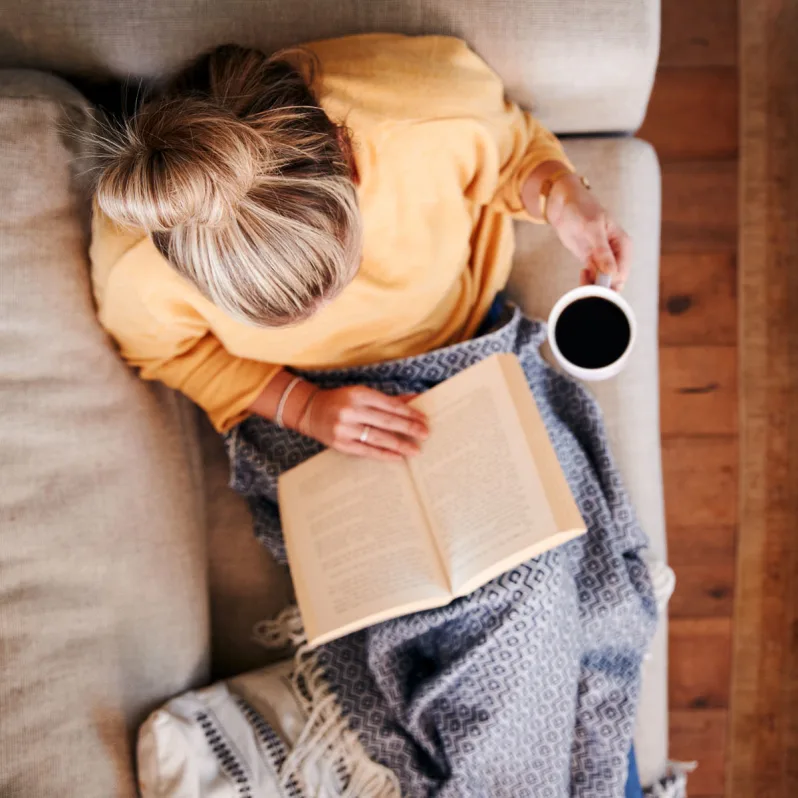 senior woman drinking coffee and reading a book