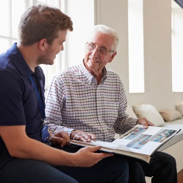 senior man looking thru photo book with aid